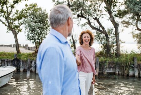 Senior couple on a holiday walking by the lake. Copy space.