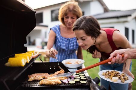 Portrait of multigeneration family outdoors on garden barbecue, grilling.の写真素材