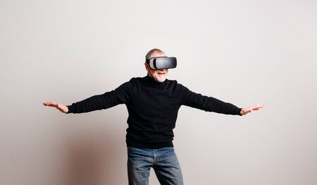 Portrait of a cheerful senior man with VR goggles in a studio.の写真素材
