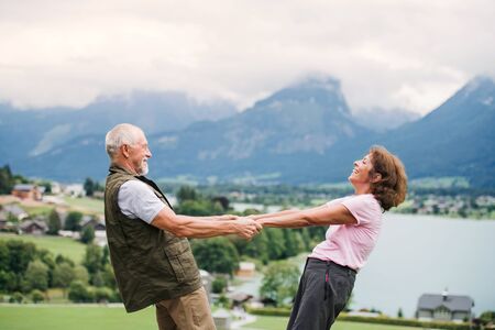 A senior pensioner couple hiking in nature, holding hands.の写真素材