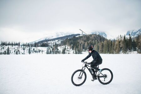 Side view of mountain biker riding in snow outdoors in winter nature.の写真素材