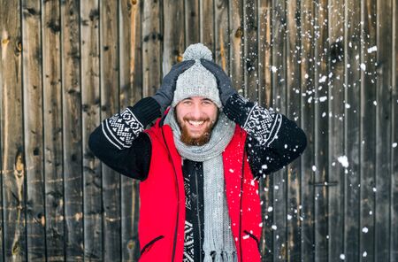Young man standing against wooden background outdoors in winter.の写真素材