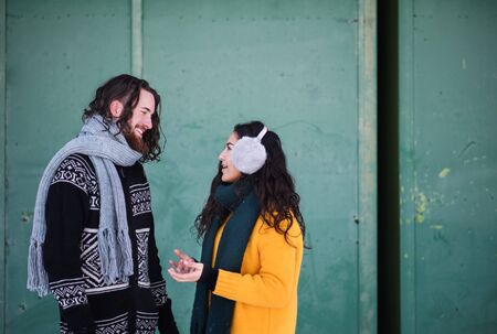 A portrait of couple standing outdoors in winter, talking.の写真素材