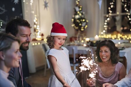 Small girl with parents and grandparents indoors celebrating Christmas.の写真素材