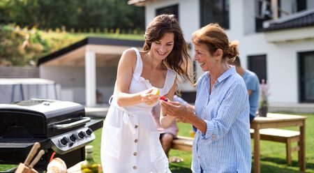 Portrait of multigeneration family outdoors on garden barbecue, grilling.の写真素材
