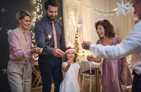 Small girl with parents and grandparents indoors celebrating Christmas.