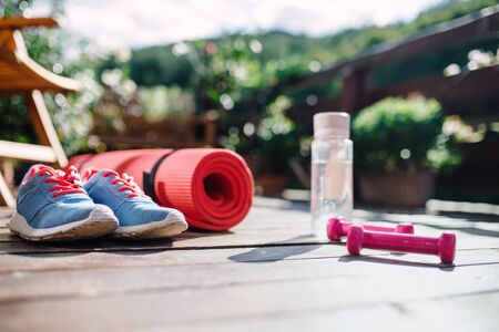 Water bottle, trainers and dumbbells outdoors on a terrace in summer.の写真素材