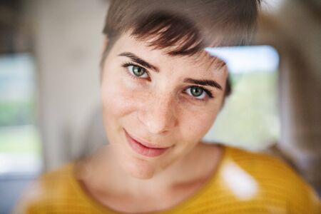 Front view of young woman standing indoors at home, close-up.の写真素材
