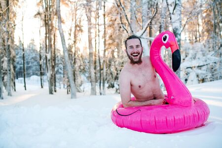 Topless young man outdoors in snow in winter forest, having fun.の写真素材