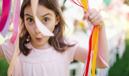 Small girl standing outdoors in garden in summer, birthday celebration concept.の写真素材