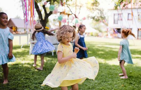 Small children standing outdoors in garden in summer, playing.の写真素材