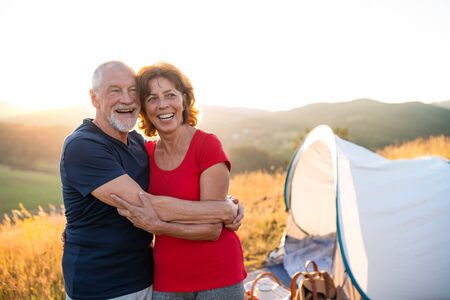 Senior tourist couple standing in nature at sunset, resting.の写真素材