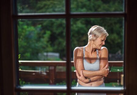 A senior woman with sports bra standing outdoors on a terrace in summer.の写真素材