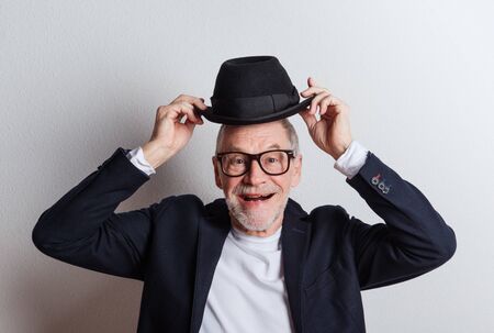 Portrait of a senior man with hat and glasses in a studio.の写真素材