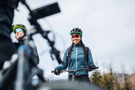 Group of mountain bikers standing on road outdoors in winter, talking.の写真素材