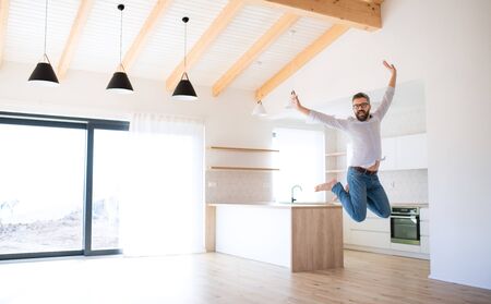 Cheerful mature man moving in new unfurnished house, jumping.の写真素材