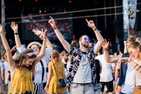 Front view portrait of group of young friends dancing at summer festival.