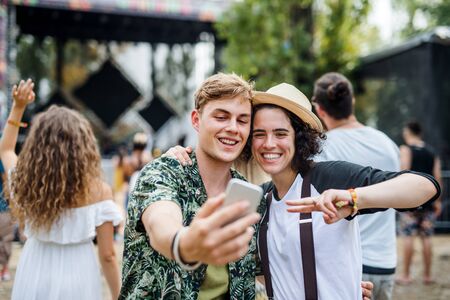 Young couple at summer festival, taking selfie with smartphone.の写真素材
