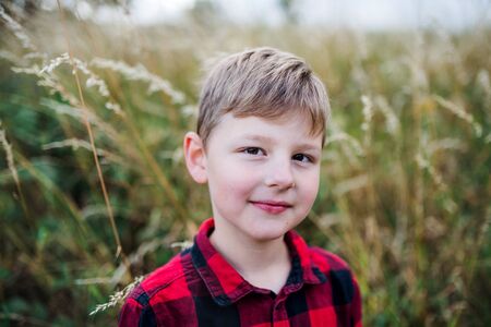 A portrait of school boy standing in nature, looking at camera.の写真素材