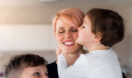 A young woman with two children indoors at home, having fun.の写真素材