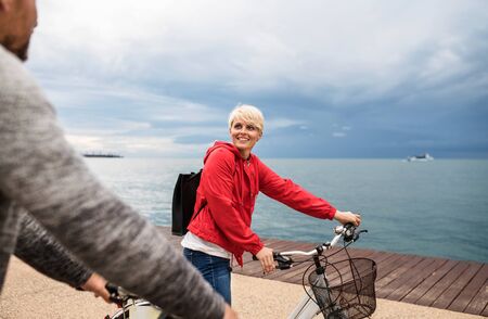Couple with bicycles outdoors on beach, talking. A midsection.