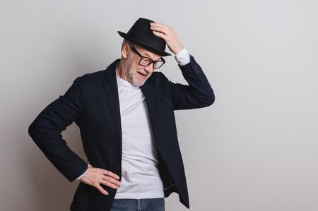 Portrait of a senior man with hat and glasses in a studio.の写真素材