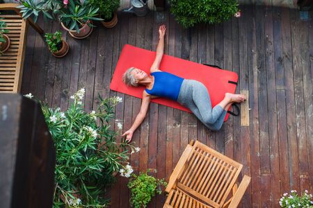 A top view of senior woman outdoors on a terrace in summer, doing exercise.の写真素材