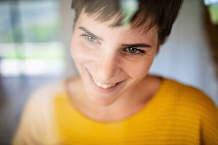 Front view of young woman standing indoors at home, close-up.の写真素材