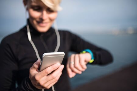 A young sportswoman with smartphone standing outdoors on beach.の写真素材