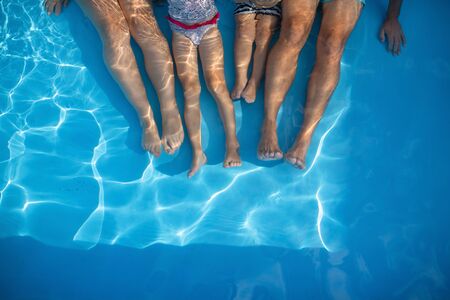 Midsection of family with small children sitting in swimming pool outdoors.の写真素材