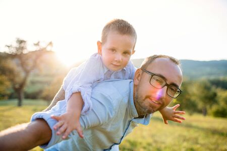 Father with small toddler son on walk on meadow outdoors, having fun.の写真素材