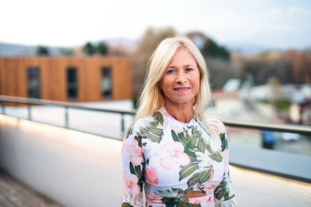 A senior woman standing outdoors, looking at camera.