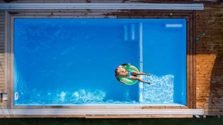 Aerial view of man with sunglasses lying in water in swimming pool outdoors.の写真素材