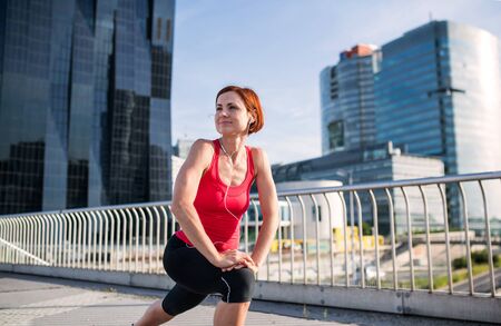 Young woman doing exercise on bridge outdoors in city, stretching.の写真素材