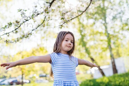 A cheerful small girl playing outside in spring nature.の写真素材