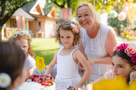 Small children sitting at the table outdoors on garden party.