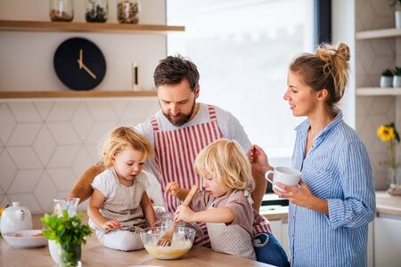 Young family with two small children indoors in kitchen, cooking.の写真素材
