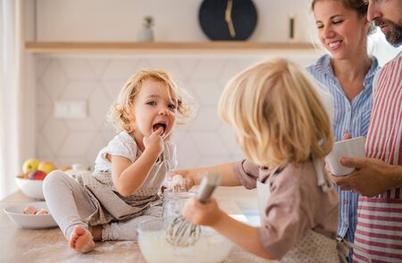 Young family with two small children indoors in kitchen, cooking.の写真素材