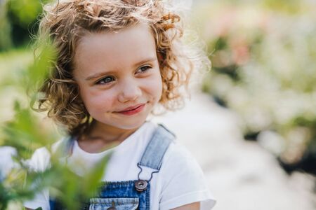 Portrait of small girl standing in the backyard garden.の写真素材