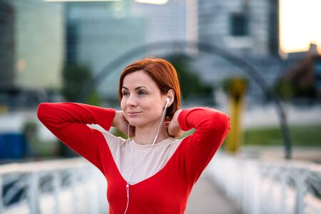 Front view of young woman runner with earphones in city, resting.の写真素材