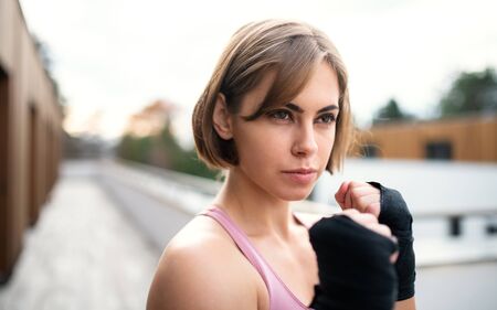 A young woman practising karate outdoors on terrace.