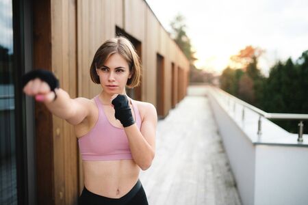 A young woman practising karate outdoors on terrace.