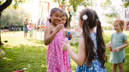 Small children standing outdoors in garden in summer, playing.の写真素材