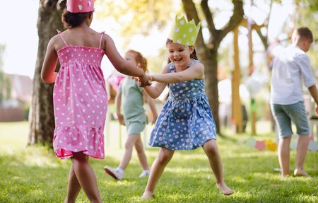 Small children standing outdoors in garden in summer, playing.の写真素材