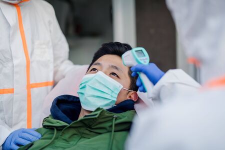 People with protective suits helping man outdoors, coronavirus concept.の写真素材