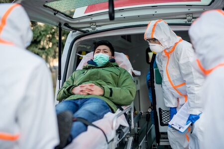 People with protective suits helping man outdoors, coronavirus concept.の写真素材