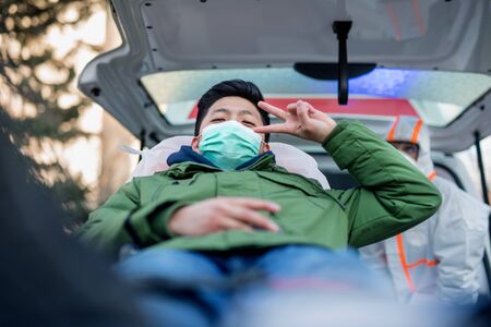 Man on stretcher by ambulance outdoors, coronavirus concept.の写真素材