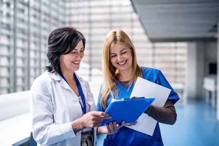 Women doctors standing in corridor on medical conference, talking.の写真素材