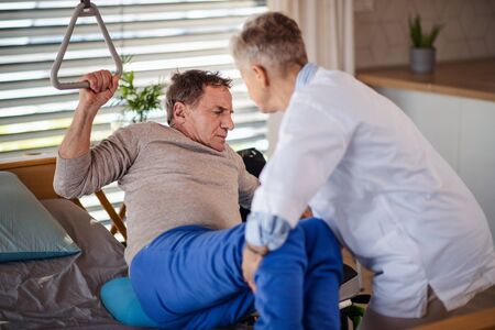 A healthcare worker helping paralysed senior patient in hospital.