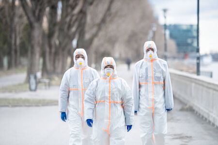 People with protective suits walking outdoors, coronavirus concept.